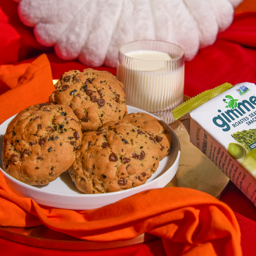 Cookies on a plate next to a glass of milk and gimme olive oil roasted seaweed snack.