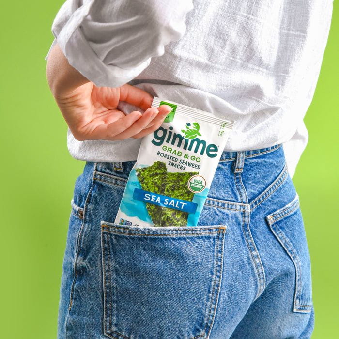 A person places a packet of "gimMe" roasted seaweed snacks into their back jeans pocket.