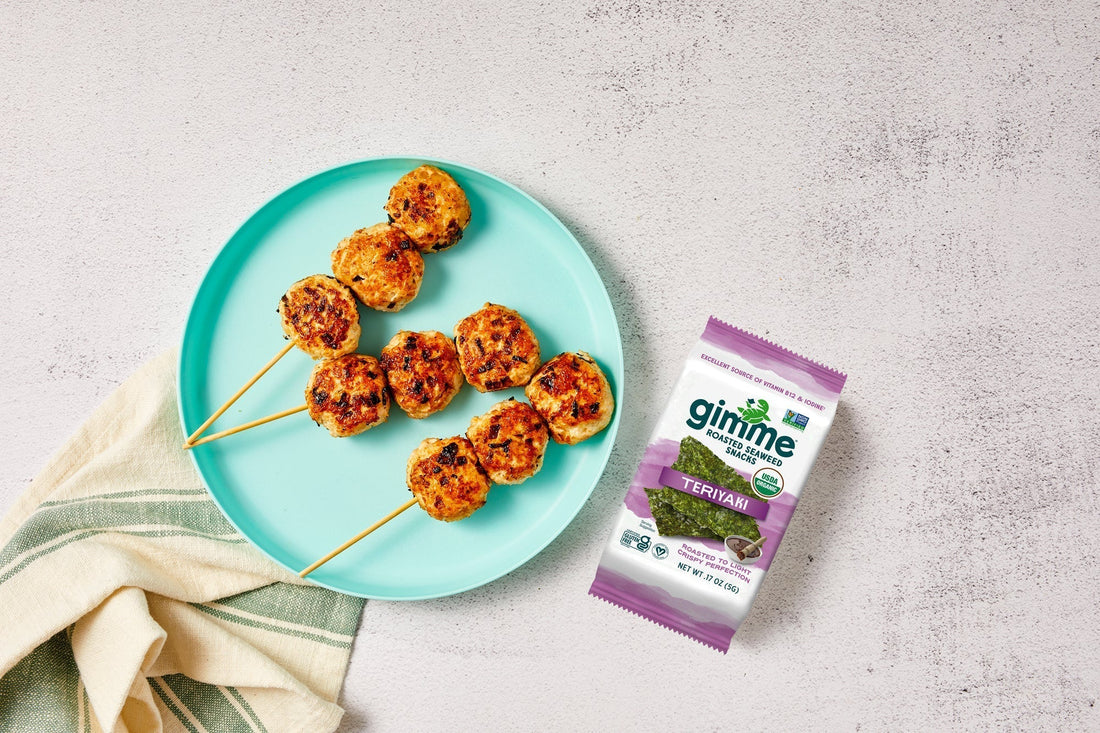 Chicken meatballs on skewers on a plate with gimme teriyaki seaweed snack.