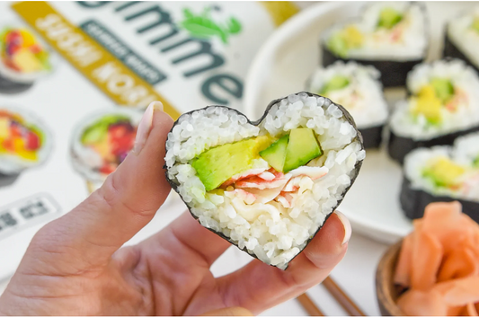 Woman's hand holding a heart-shaped sushi roll